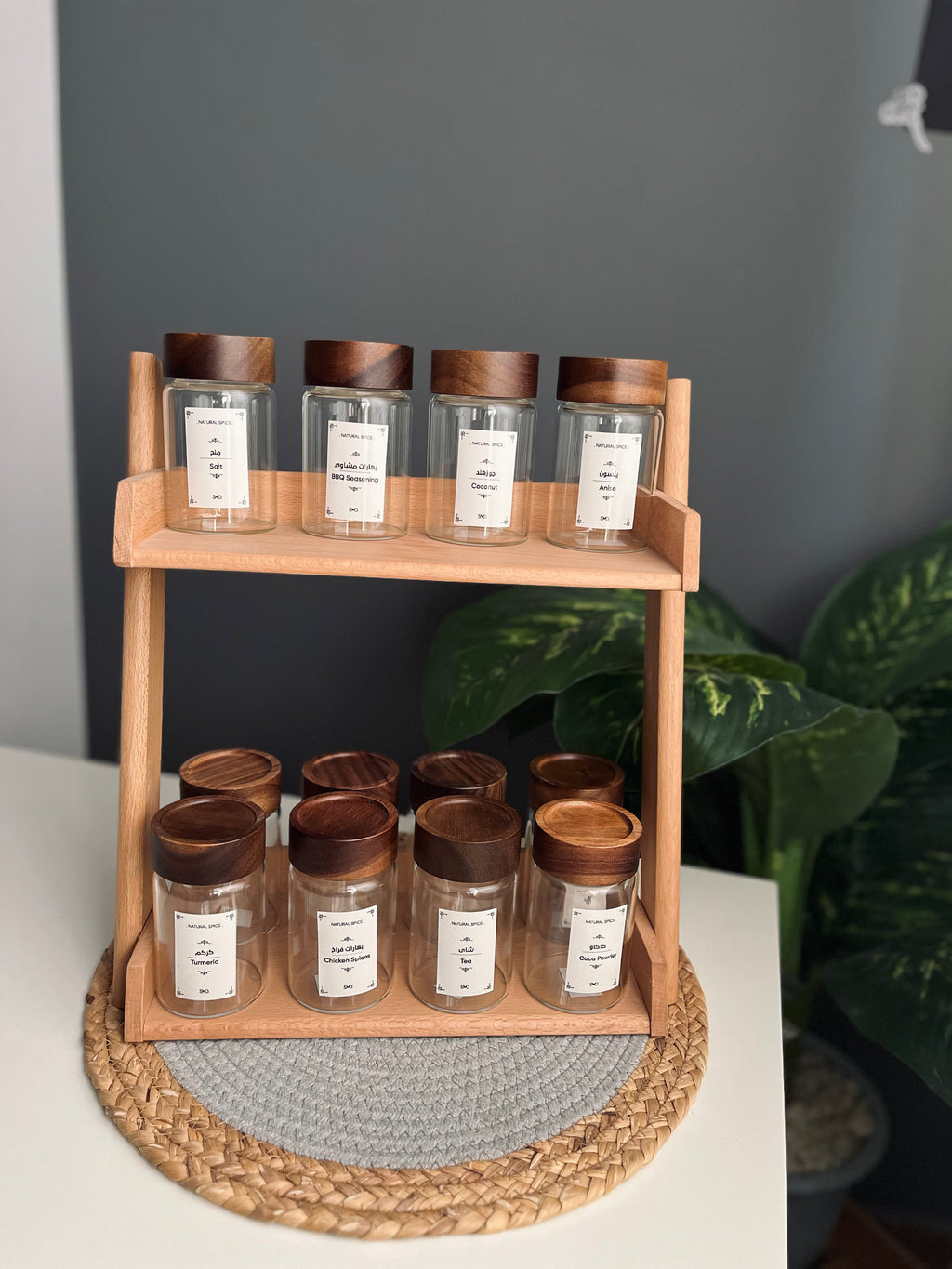 Wooden tiered kitchen counter shelf organizer displaying 12 large clear 300ml glass spice jars with custom labeling stickers