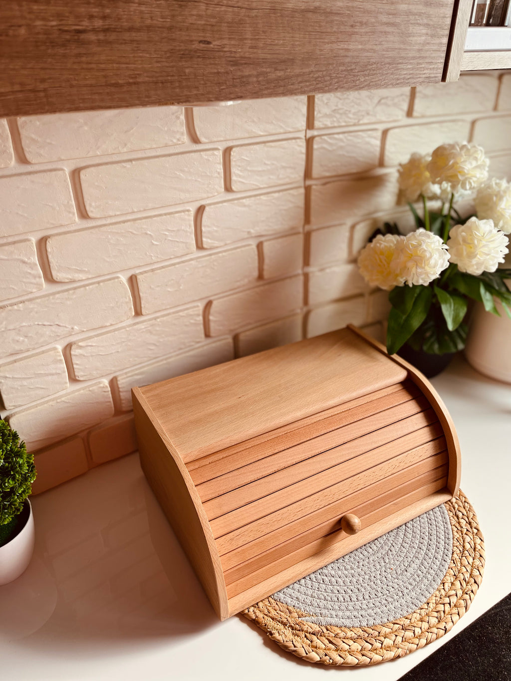 Natural beech wood bread box storage bin sitting on a kitchen counter