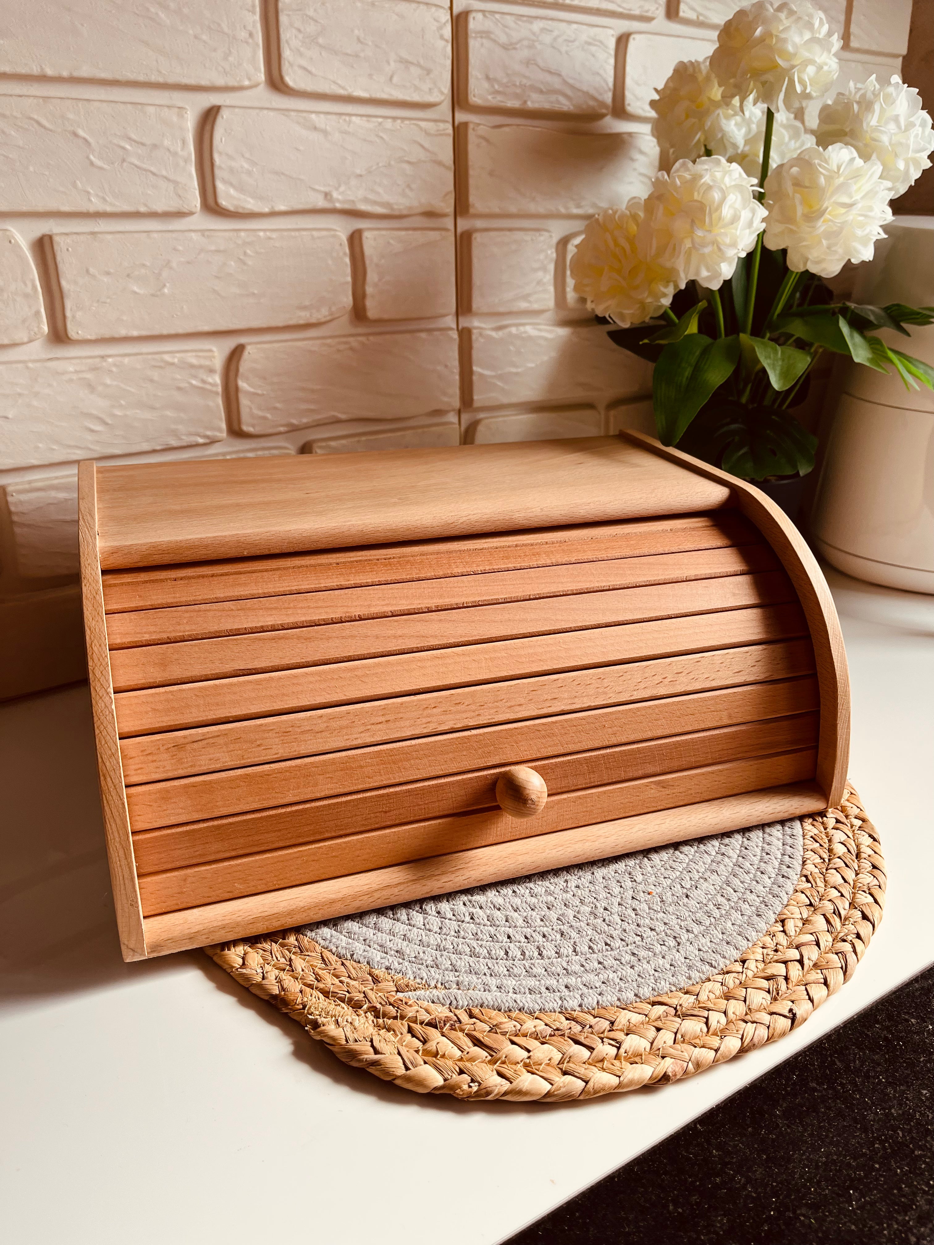 Natural beech wood bread box storage bin sitting on a kitchen counter